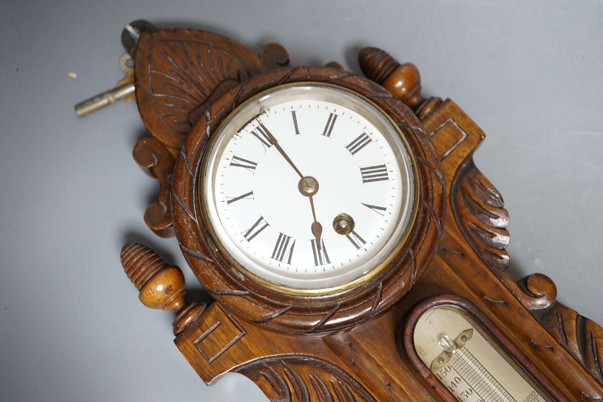 A Victorian carved walnut aneroid barometer with timepiece